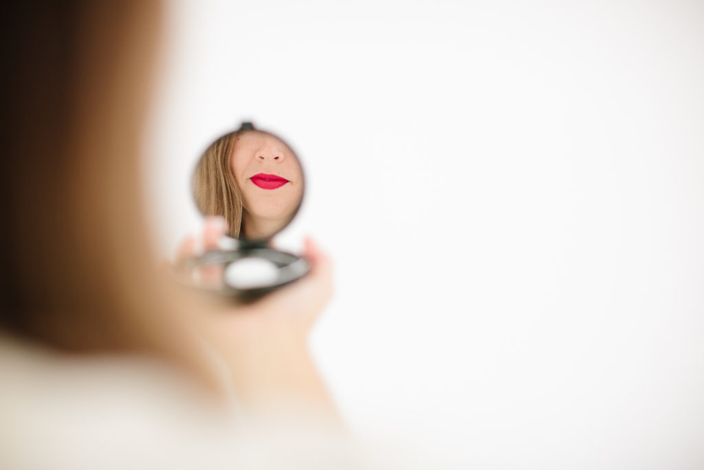 woman looking in a compact mirror at herself